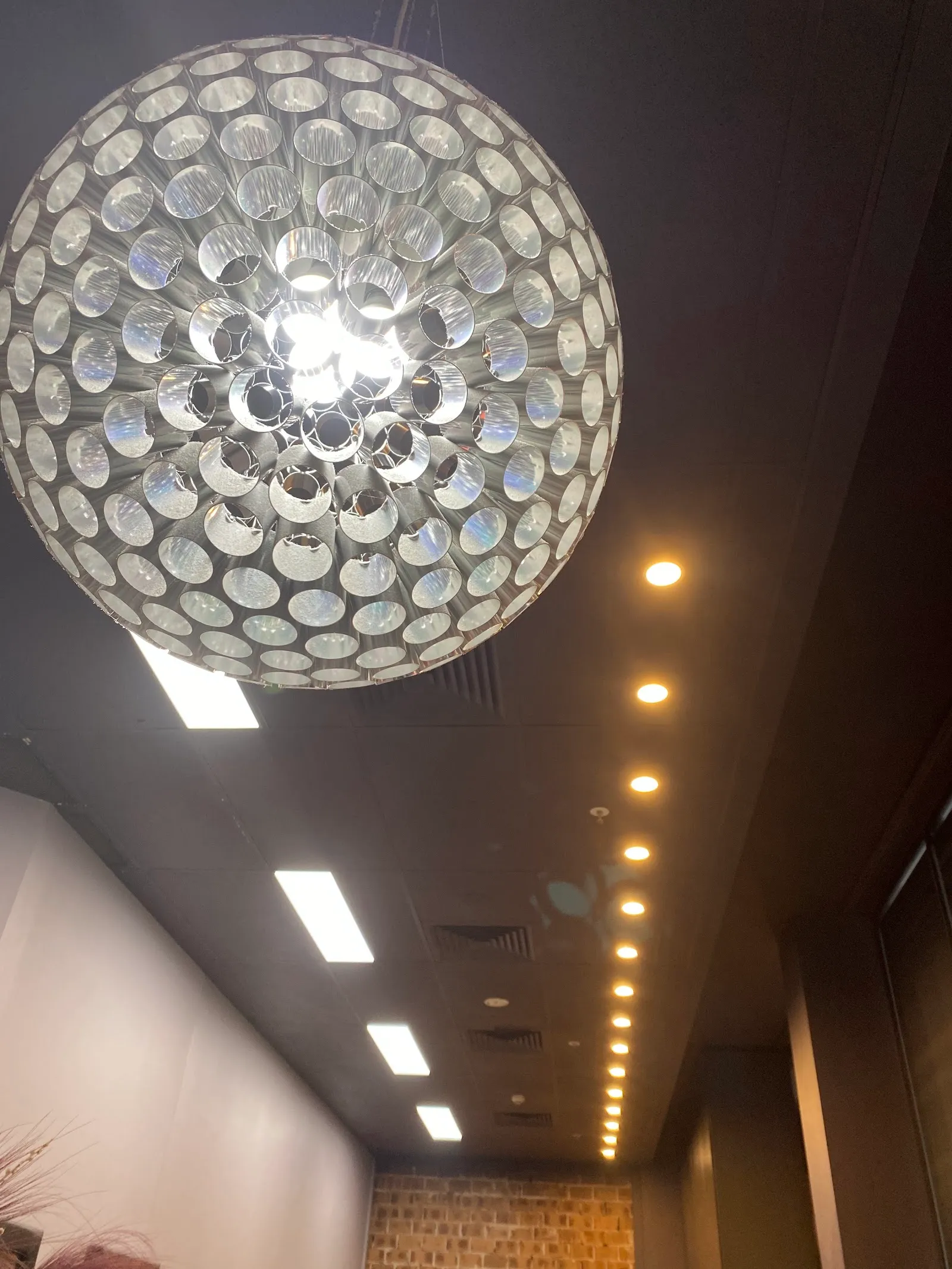 A round crystal-bead pendant light above a row of ceiling downlights in the salon