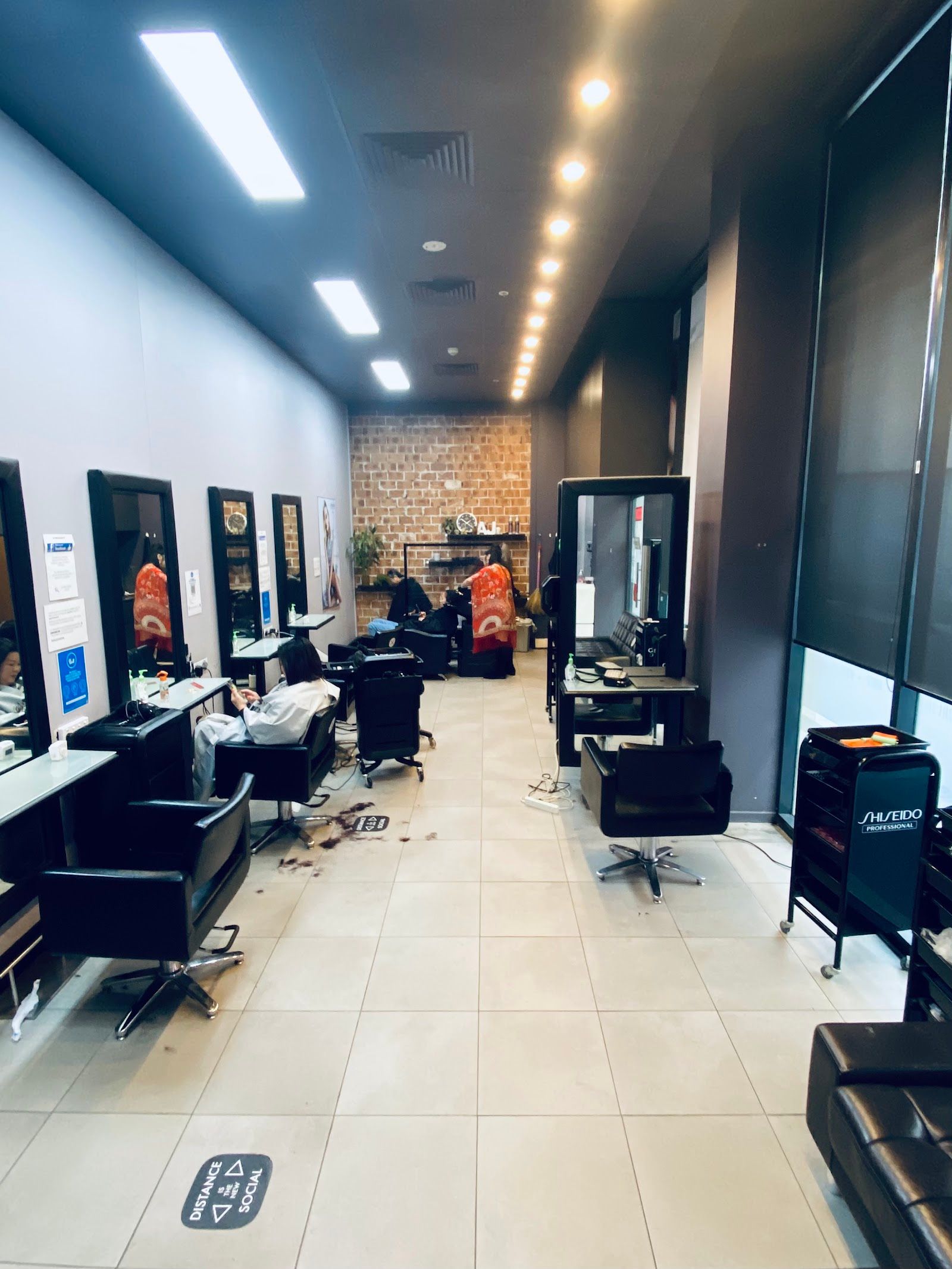 The salon floor at A J Hair & Beauty Salon, with styling stations along a long room under ceiling lights