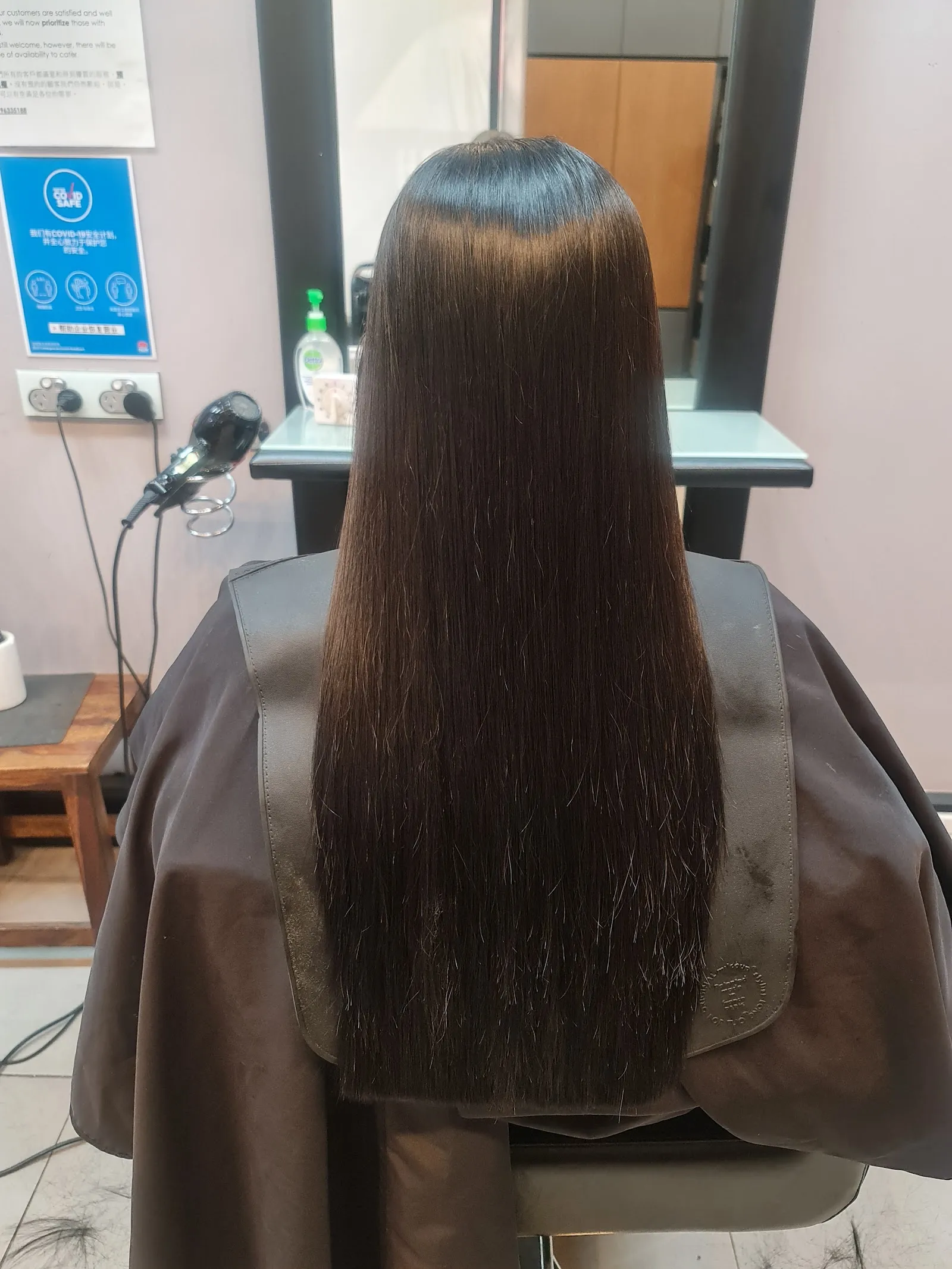 Long, straight brown hair seen from behind, in a styling chair